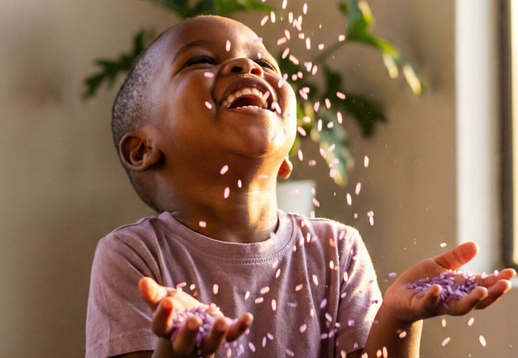 Child letting lavender rice fall through fingers during sensory play.