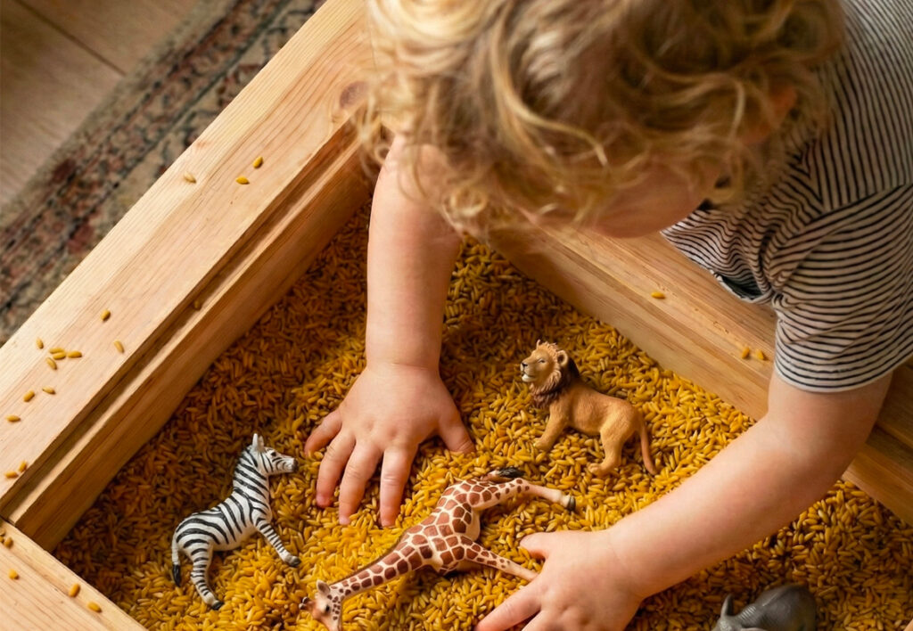 Toddler digging for safari animals in mustard yellow rice.